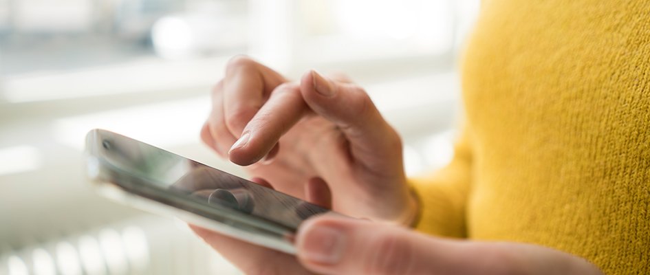 person in yellow shirt tapping mobile phone up close