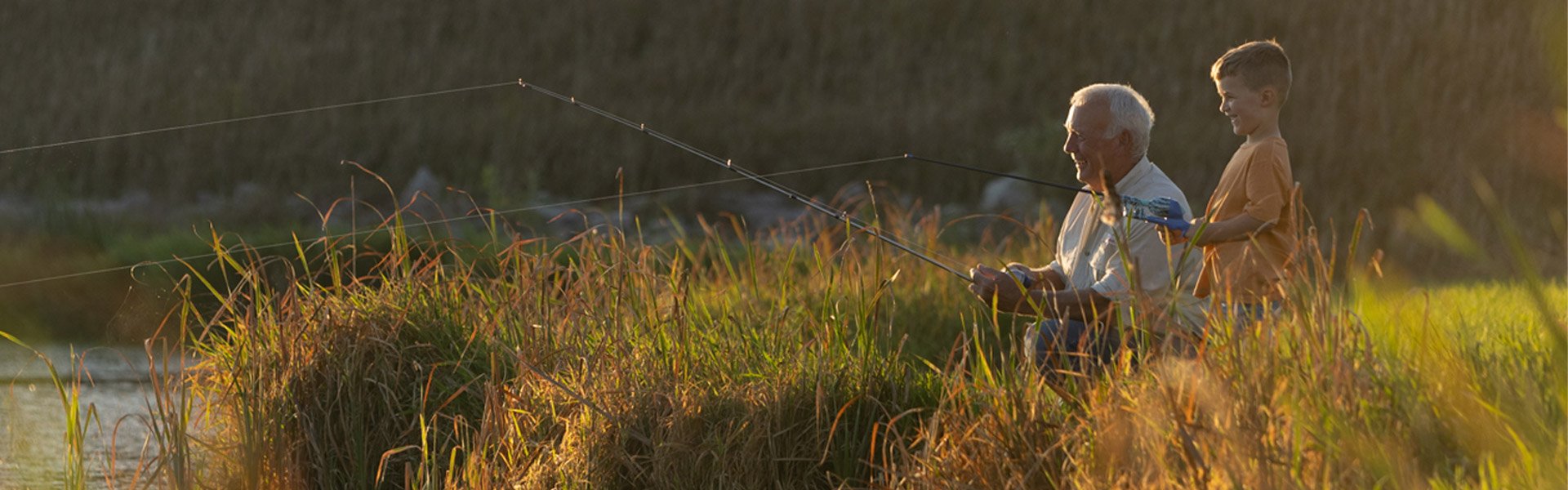 Grandfather and grandson fishing in a rural environment