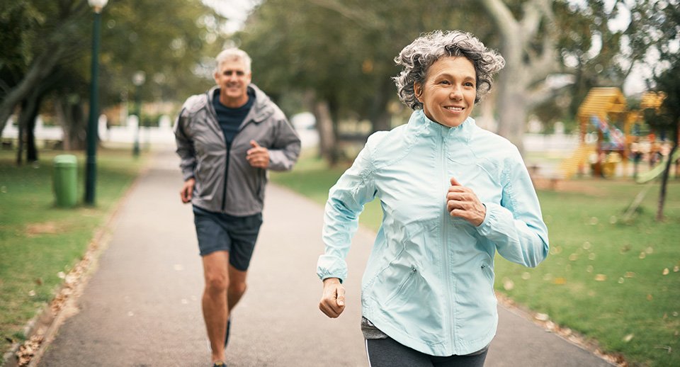 Man and woman jogging through a park.