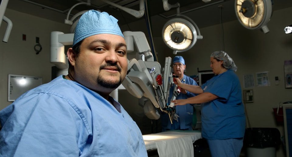 Dr Luis Rojas in front of robotic surgical machine.