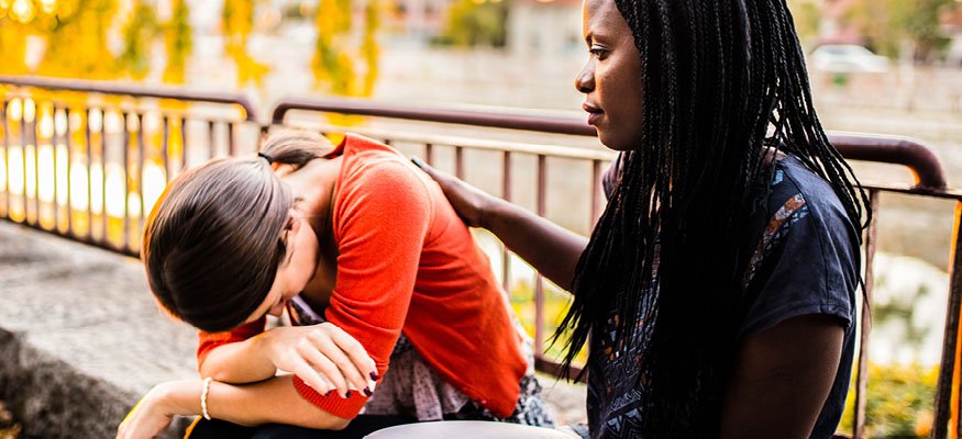 woman comforting teen with head down