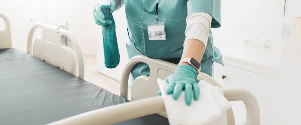 employee cleaning hospital bed