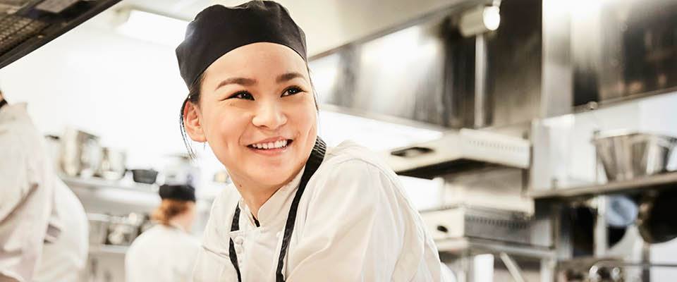 food service worker in hospital kitchen smiling.