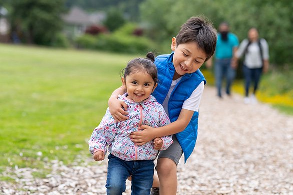 two kids walking parents in background