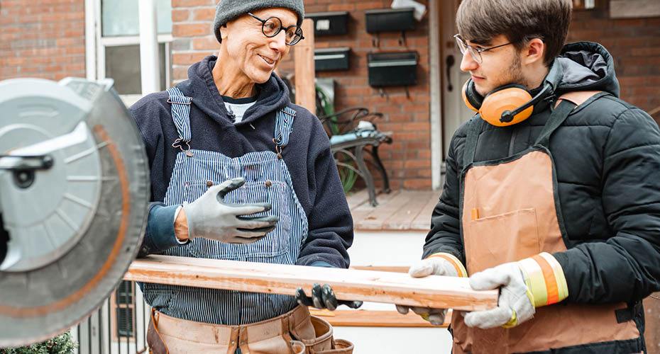 Two men talking and sawing wood