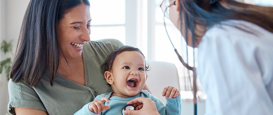 baby on moms lap being examined by doctor.