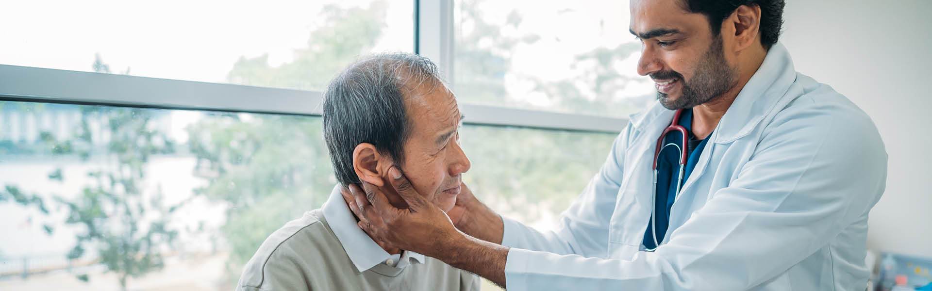 male doctor examining patient's neck.