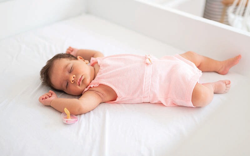 Baby sleeping on back in crib