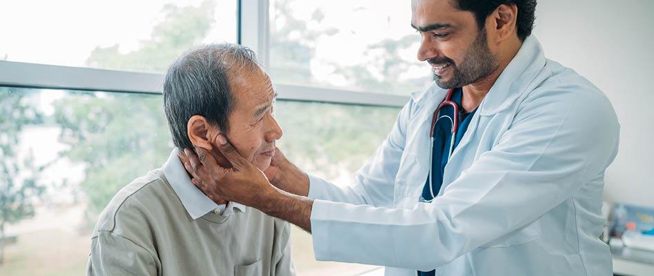 male doctor examining patient's neck.