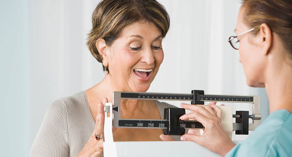 Woman smiling while having her weight measured.